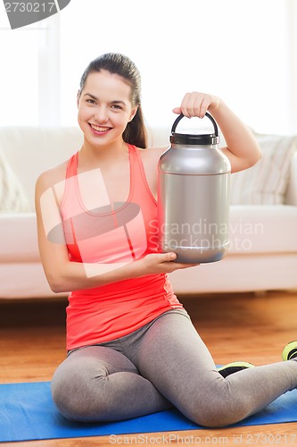 Image of smiling teenage girl with jar of protein at home