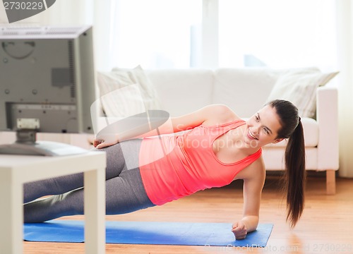 Image of smiling teenage girl doing side plank at home