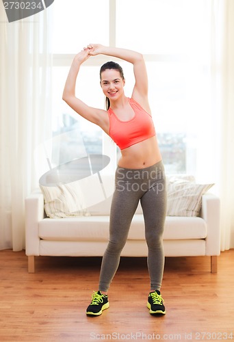 Image of smiling teenage girl streching at home