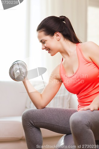 Image of smiling girl exercising with dumbbells