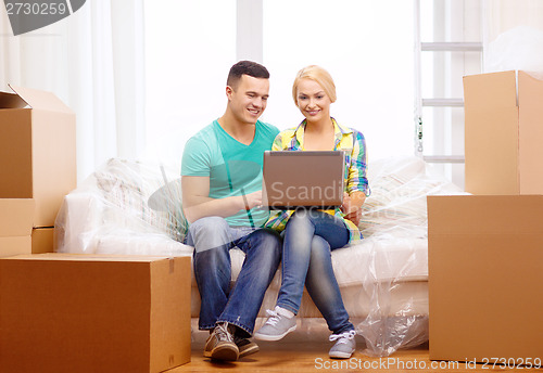 Image of couple relaxing on sofa with laptop in new home