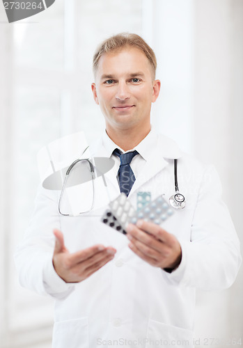 Image of young male doctor with packs of pills