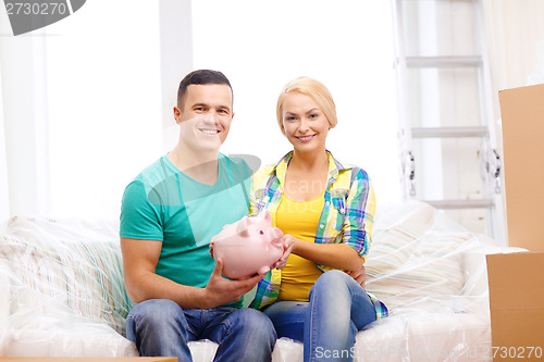 Image of smiling couple with piggybank in new home