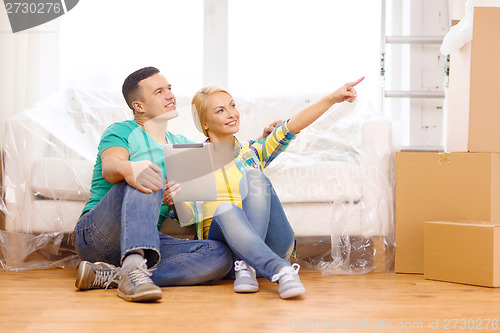 Image of smiling couple with tablet pc in new home