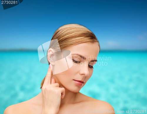 Image of calm woman touching her ear