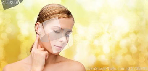 Image of calm woman touching her ear