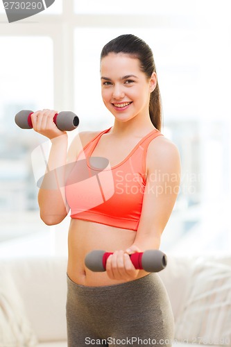 Image of smiling teenage girl exercising with dumbbells