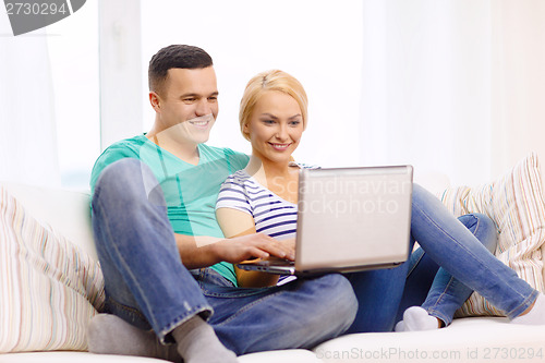 Image of smiling happy couple with laptop at home