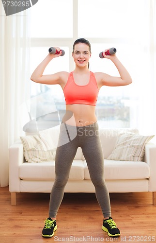 Image of smiling teenage girl exercising with dumbbells