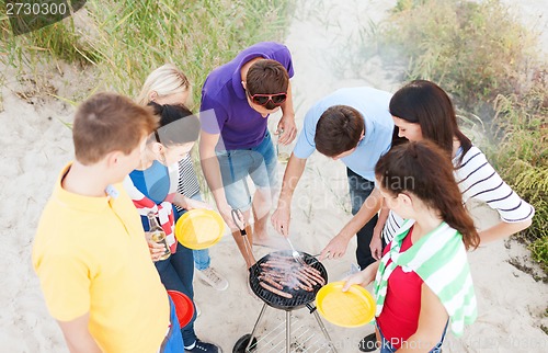 Image of group of friends having picnic and making barbecue