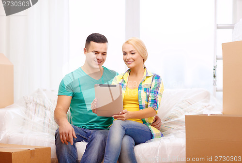 Image of couple relaxing on sofa with tablet pc in new home