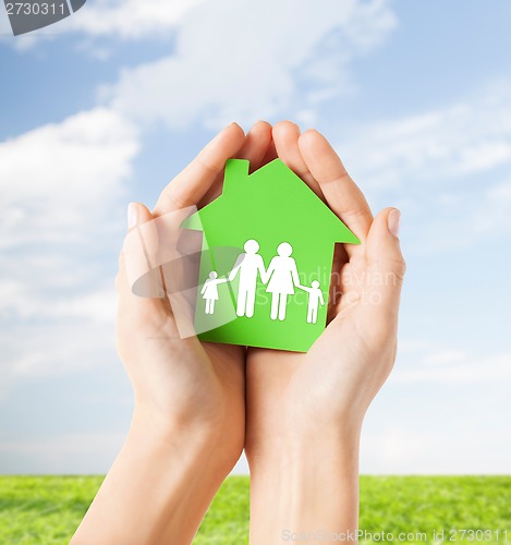 Image of hands holding green house with family