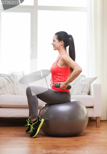 Image of smiling girl exercising with fitness ball