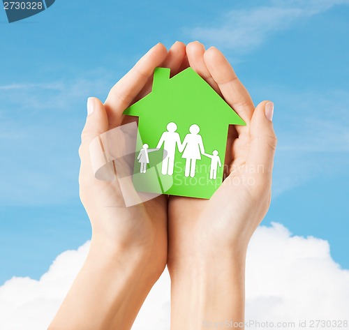 Image of hands holding green house with family