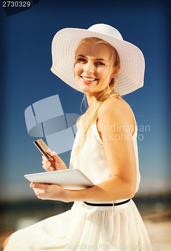 Image of woman in hat doing online shopping outdoors