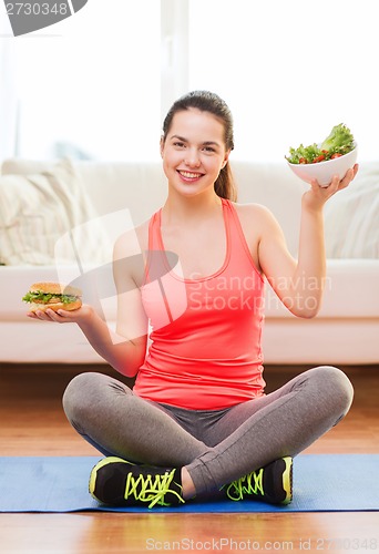 Image of smiling teenager with green salad and hamburger