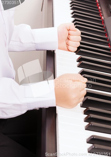 Image of close up of child hands in fists hitting the piano