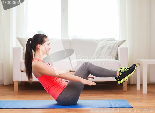 Image of smiling girl doing exercise on floor at home