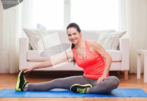 Image of smiling teenage girl streching on floor at home