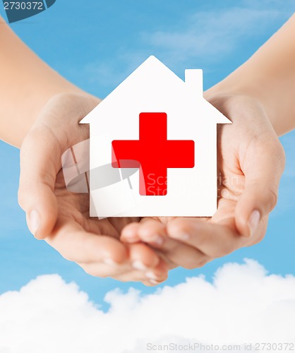 Image of hands holding paper house with red cross