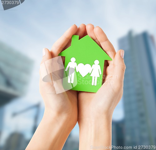 Image of hands holding green house with family