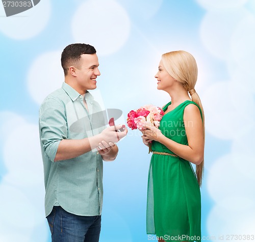 Image of smiling couple with flower bouquet and ring