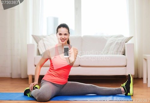 Image of smiling teenage girl streching on floor at home