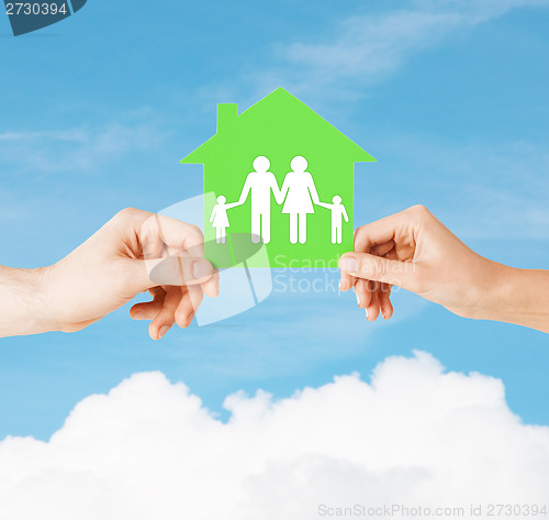 Image of hands holding green house with family