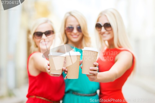 Image of blonds holding takeaway coffee cups in the city