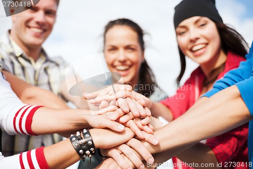 Image of teenagers hands on top of each other outdoors