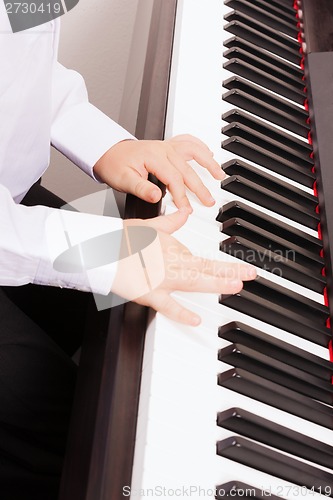 Image of close up of child hands playing the piano