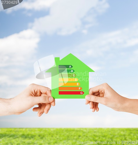 Image of hands holding green paper house