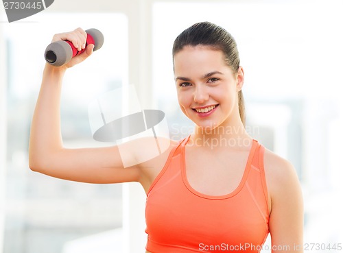 Image of smiling teenage girl exercising with dumbbell