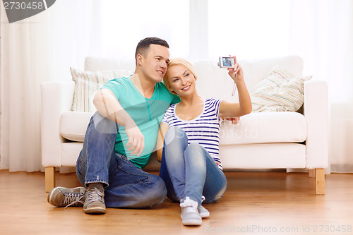 Image of smiling couple taking picture with digital camera
