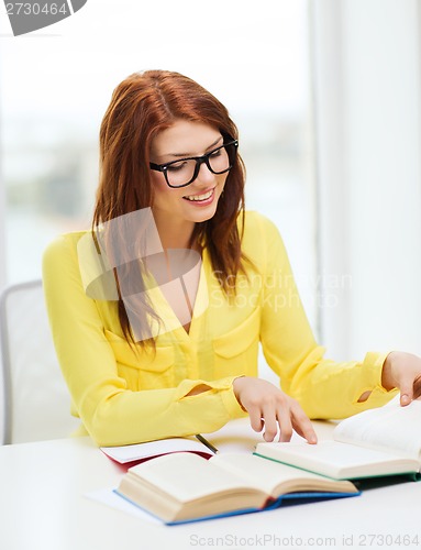 Image of smiling student girl reading books in college