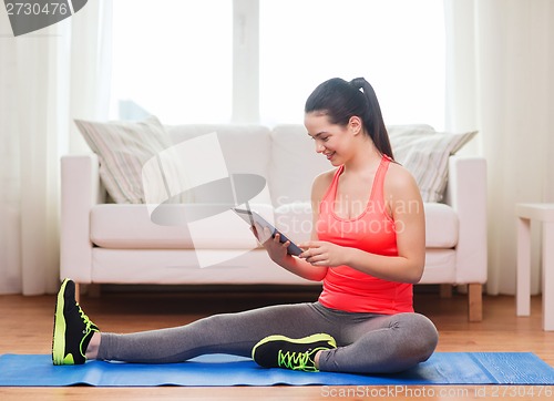 Image of smiling teenage girl streching on floor at home