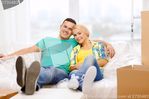 Image of smiling couple relaxing on sofa in new home