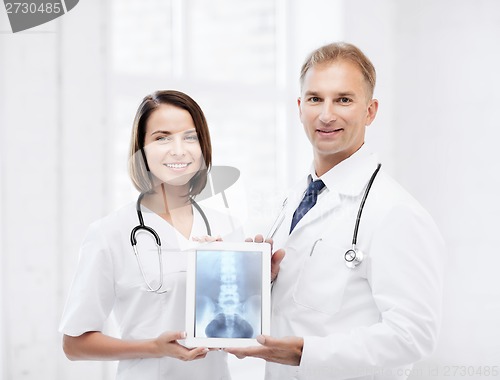 Image of two doctors showing x-ray on tablet pc