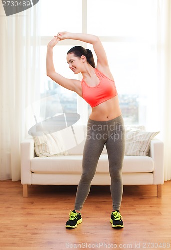 Image of smiling teenage girl streching at home