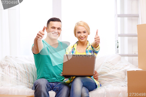 Image of couple relaxing on sofa with laptop in new home