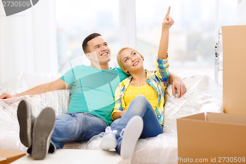 Image of smiling couple relaxing on sofa in new home