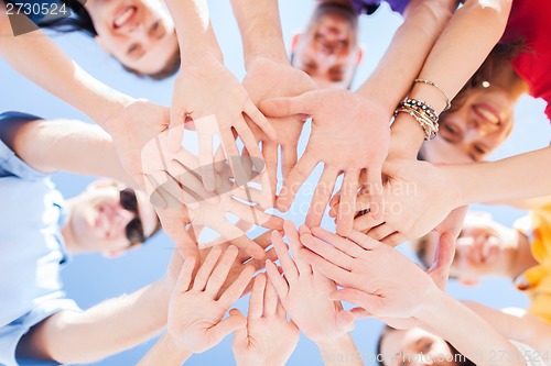 Image of teenagers hands on top of each other outdoors