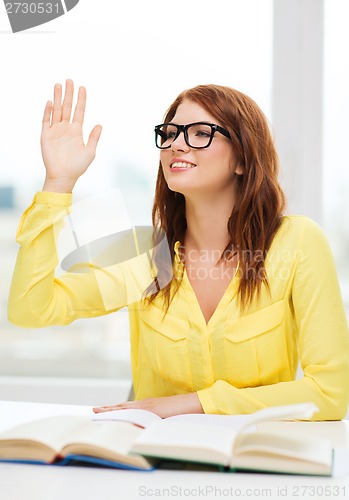 Image of smiling student girl with books and raised hand