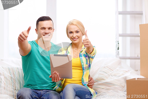 Image of couple relaxing on sofa with tablet pc in new home