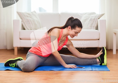 Image of smiling teenage girl streching on floor at home