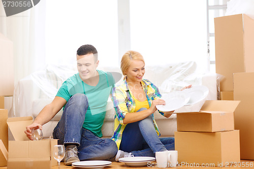 Image of smiling couple unpaking boxes with kitchenware