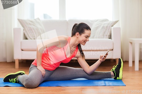 Image of smiling teenage girl streching on floor at home