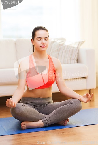Image of smiling teenager meditating at home