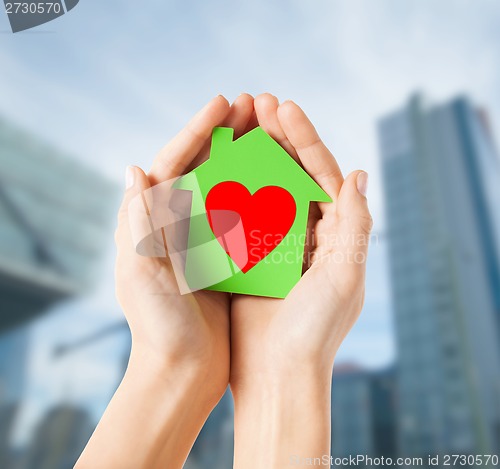 Image of hands holding green paper house