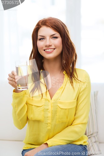 Image of smiling teenager with glass of water at home